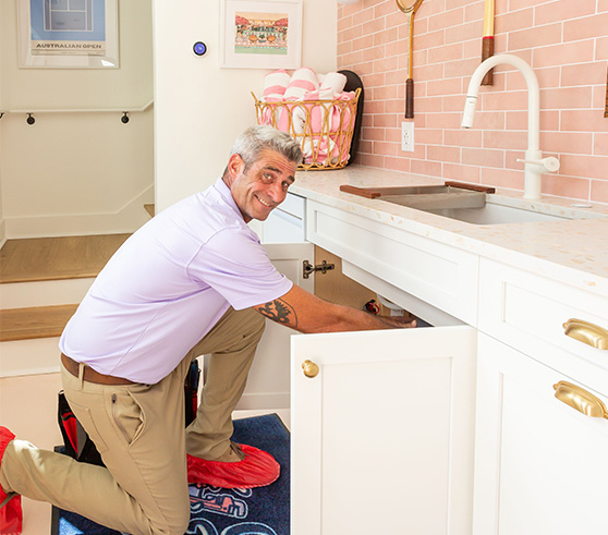 Picture of a Charles Towne Plumbing expert smiling while cleaning a drain.