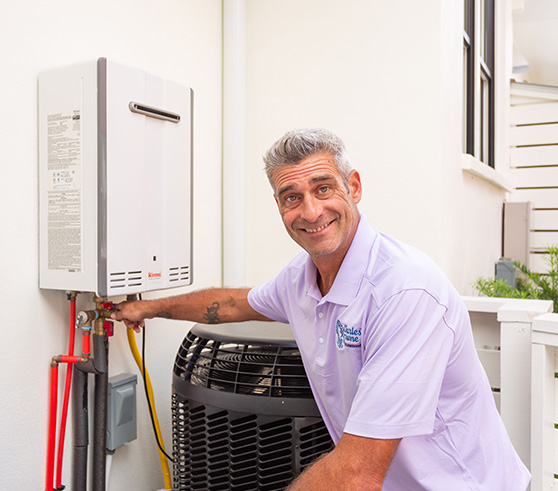 Picture of a Charles Towne Plumbing expert smiling while fixing a water heater.
