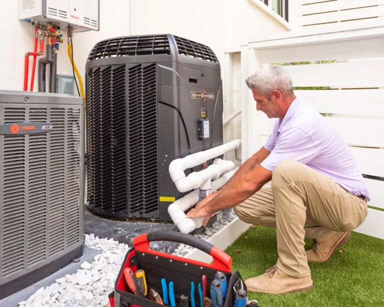 Technician repairing outdoor heat pump unit, surrounded by tools and equipment.